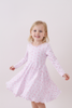 Young girl wearing a pink dress with a subtle pattern on a white background