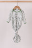 Green and white patterned baby outfit on a hanger against a light background